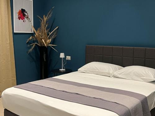 a bedroom with a bed with a blue wall at Sunset Palace Guesthouse in Reggio Calabria
