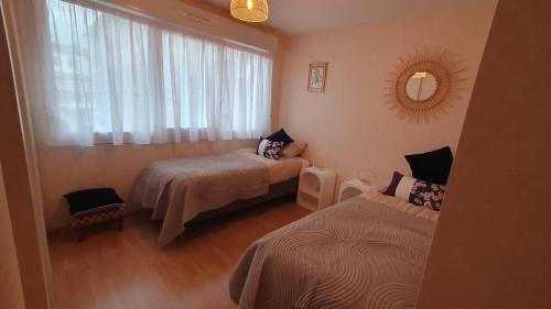 a small room with two beds and a window at La terrasse de Jeanne in Millau