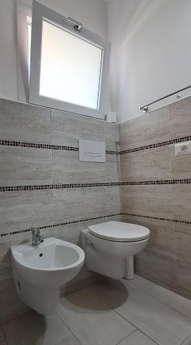 a bathroom with a toilet and a sink and a window at Al Mare da Francesca in Olbia