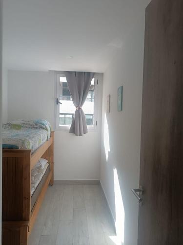 a bedroom with a bed and a window with a curtain at Zeus II Pinamar in Pinamar