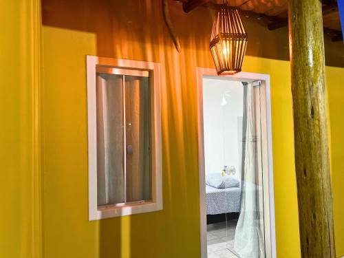 a yellow room with a mirror and a bedroom at Casa de temporada Bem-Te-Vi in Porto Seguro