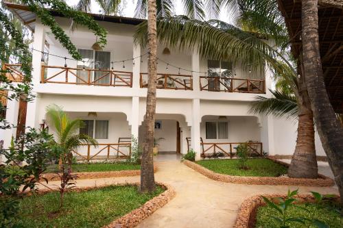 a white building with palm trees in front of it at African Bungalows in Nungwi