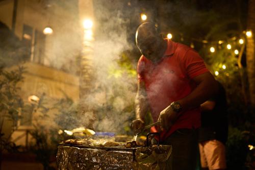 a man cooking food on top of a grill at African Bungalows in Nungwi
