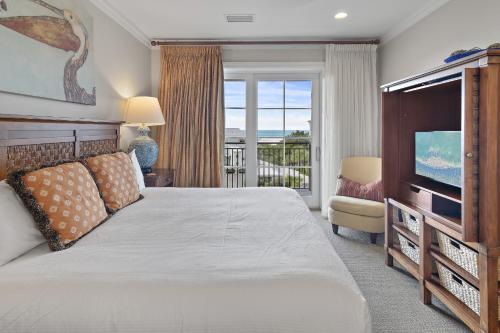 a bedroom with a bed and a television and a balcony at WaterHouse 402 in Inlet Beach