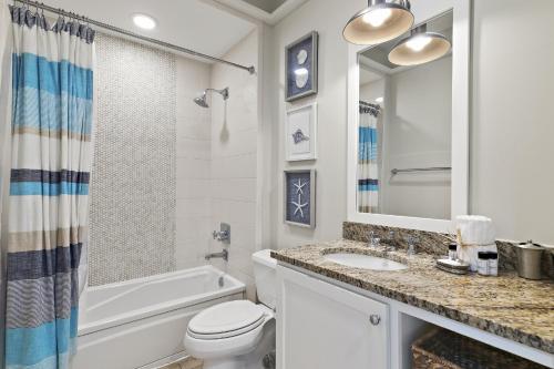 a white bathroom with a sink and a toilet and a tub at WaterHouse 402 in Inlet Beach
