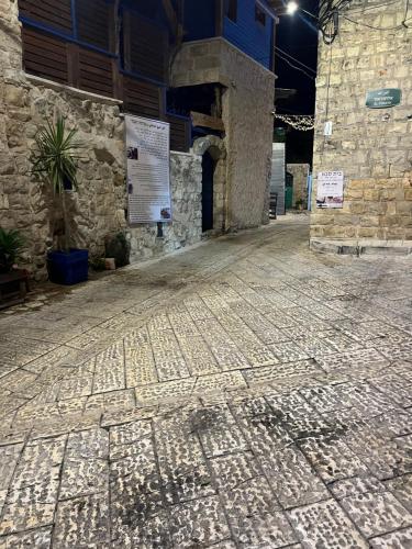 an empty street with a stone building withcriptions on it at לומינוס הגפן in Ḥurfeish