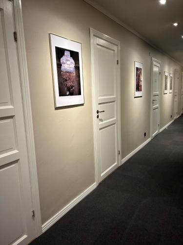 a hallway with white doors and pictures on the wall at Äppelgården i Båstad in Båstad