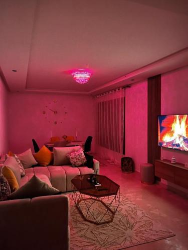 a pink living room with a couch and a tv at Beautiful Apartment with Seaside Pool in Mansouria