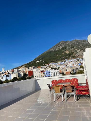 a balcony with a table and chairs and a view of a city at Casa Abdou in Chefchaouene