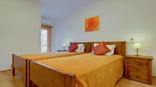 ein Schlafzimmer mit einem großen Bett mit orangefarbener Bettwäsche in der Unterkunft Vilamoura - Apartment near Mariana & Falesia Beach in Quarteira