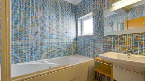 ein blau gefliestes Bad mit einer Badewanne und einem Waschbecken in der Unterkunft Vilamoura - Apartment near Mariana & Falesia Beach in Quarteira