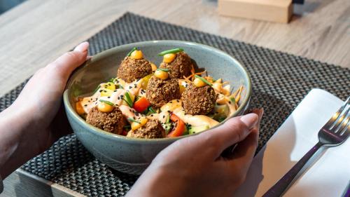 a person holding a bowl of food on a table at Radisson Blu Hotel Dortmund in Dortmund