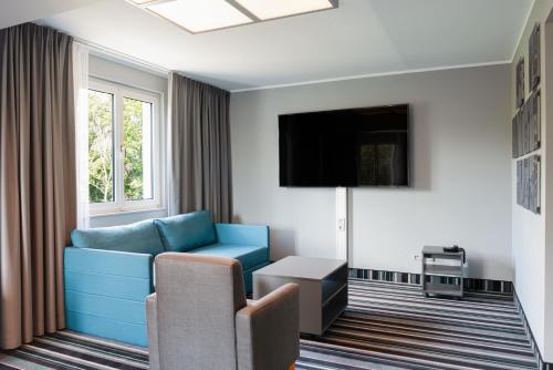 a living room with a blue couch and a tv at Radisson Blu Hotel Dortmund in Dortmund