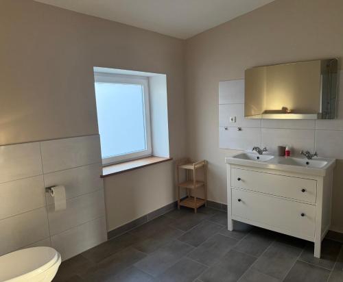 a bathroom with a toilet and a sink and a window at Helle, große Unterkunft in ländlicher Umgebung in Sterup