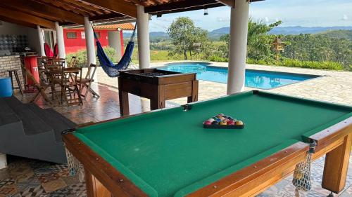 a pool table in front of a swimming pool at Chácara Recanto dos Ipês - Igaratá in Igaratá