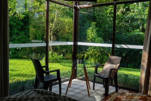 a screened in porch with chairs and a glass table at Hotel Ecopaisajes- Lake-Premier-Resort in Quesada