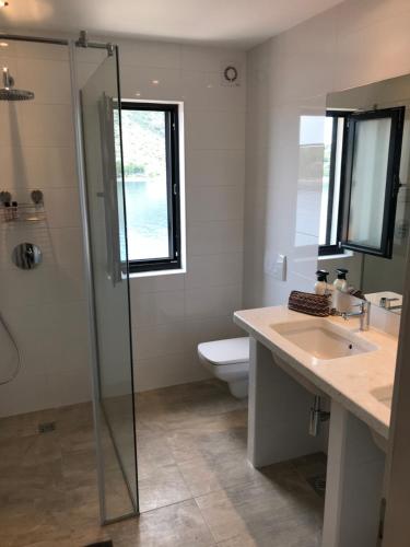 a bathroom with a shower and a toilet and a sink at Apartment White House in Vinišće