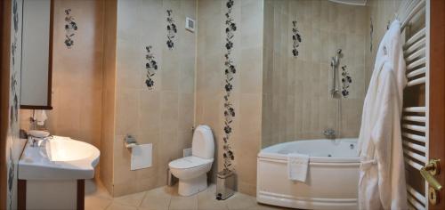 a bathroom with a tub and a toilet and a sink at Hotel Emma West in Craiova