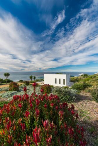 a white building in the middle of a field with flowers at Saltwater - Absolute Oceanfront, Fire Pits, some Villas with Hot Tubs and Sauna in Falmouth