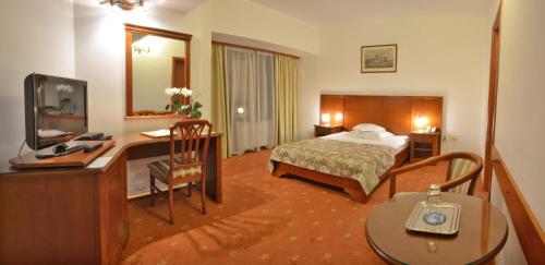 クラヨーヴァにあるHotel Emma Westのベッドとデスクが備わるホテルルームです。