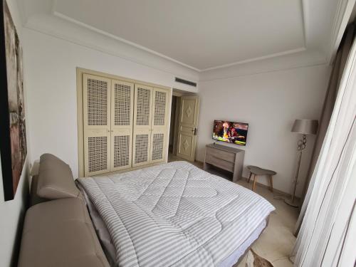 une chambre blanche avec un lit et une télévision dans l'établissement Confortable appartement S 2 à marina HAMMAMET, à Hammamet Sud