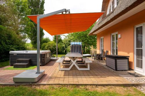 a patio with an orange umbrella and a grill at Reethaus Remy Luxus In Beckerwitz in Gramkow