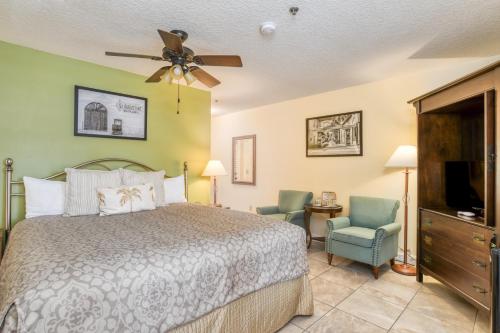 a bedroom with a bed and two chairs and a ceiling fan at St George Inn - Saint Augustine in Saint Augustine