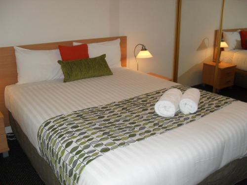 a hotel room with a large bed with towels on it at Beaches Serviced Apartments in Nelson Bay