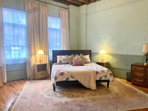 a bedroom with a bed with two lamps and two windows at Downtown Lynchburg REAL loft living Va Virginia in Lynchburg