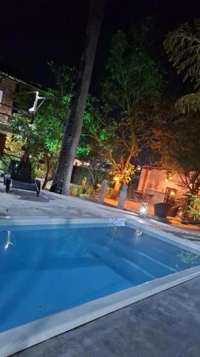 a large blue swimming pool at night with trees at Suíte 6 - Village Capixaba in Gravatá