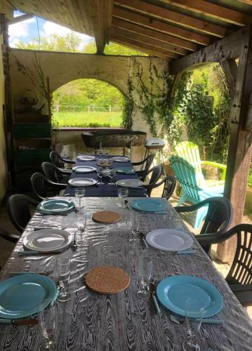 - une longue table avec des assiettes et des verres à vin dans l'établissement Cottage pleine nature, à Villebout