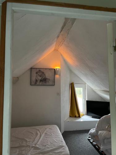 - une chambre mansardée avec un lit et une fenêtre dans l'établissement Cottage pleine nature, à Villebout