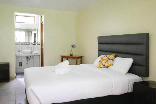 a bedroom with a large white bed and a bathroom at Mandor Machu Picchu in Machu Picchu