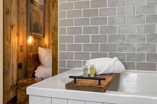 a bathroom with a bath tub and a tray with a towel at Angler's Cottage - Short Stays UK Ltd in Bridford
