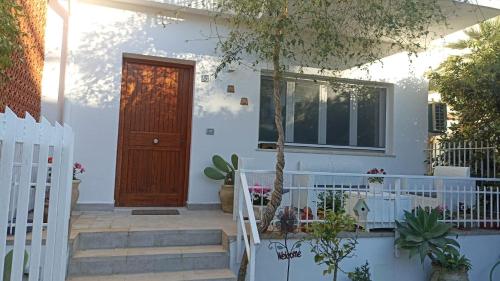 a white house with a wooden door and stairs at MONDELLO JUNO'S ROOMS in Mondello