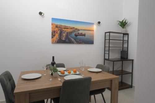 a dining room table with chairs and a painting on the wall at Stylish Valletta 1 bedooom Penthouse with Terrace in the centre with Views in Valletta