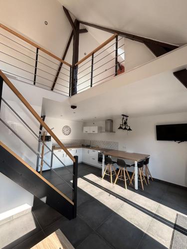 une cuisine mansardée et une salle à manger avec une table et des escaliers dans l'établissement La Hulotte 2 - Sur la route du Mont-St-Michel, à Céaux