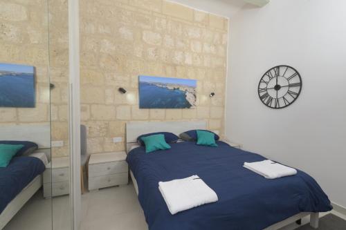 a bedroom with a blue bed and a clock on the wall at Stylish Valletta 1 bedooom Penthouse with Terrace in the centre with Views in Valletta