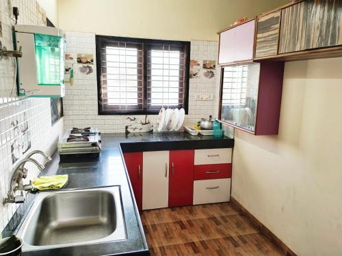 a kitchen with red and white cabinets and a sink at Maanyatha Homestay in Udupi