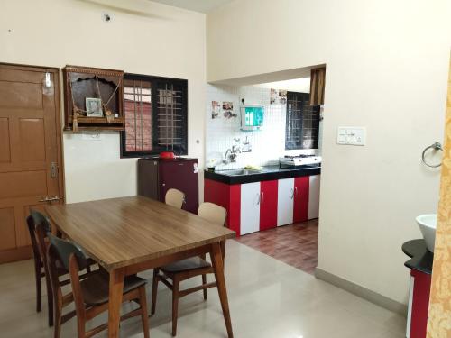a kitchen with a wooden table and a dining room at Maanyatha Homestay in Udupi