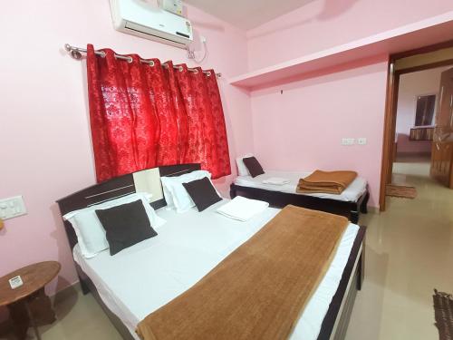 two beds in a room with a red curtain at Maanyatha Homestay in Udupi