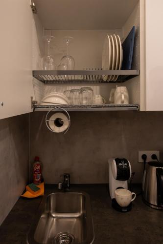 a kitchen with a sink and a shelf with dishes at Bright Vilnius Center Apartment in Vilnius