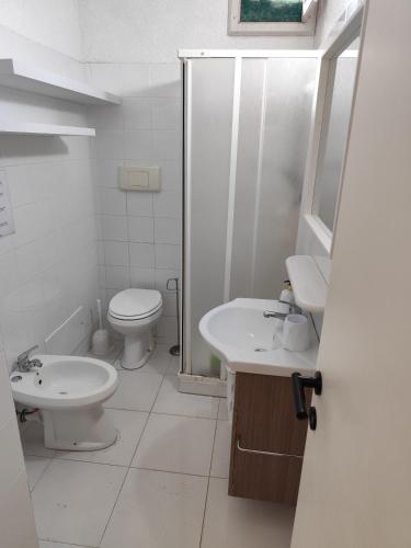 a white bathroom with a toilet and a sink at Villetta il caminetto in Geremèas