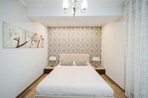 a bedroom with a white bed and a chandelier at The Central Collection Apartments in Chişinău