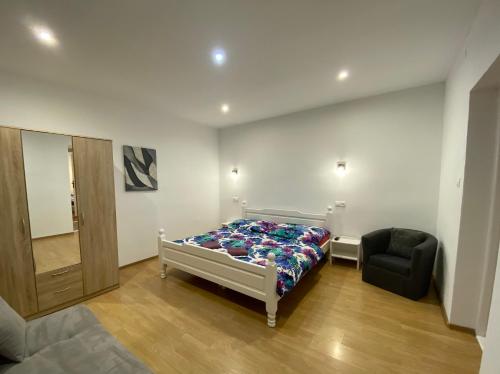 a bedroom with a bed and a black chair at Vanessa apartments in Bešeňová