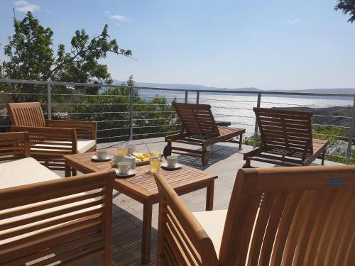 una terrazza con tavoli e sedie in legno e l'oceano di Wohnung In Cesarica Mit Privater Terrasse a Cesarica