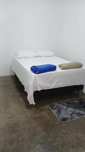 a white bed with blue sheets on it in a room at Apartamento Central in Triunfo