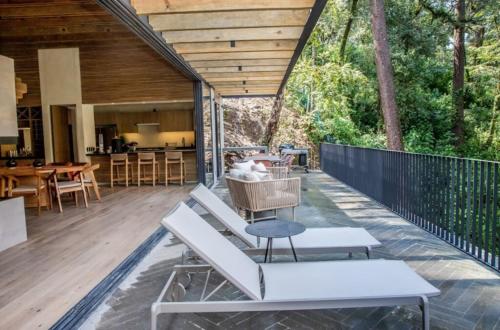 an outdoor deck with white benches and tables at Riverside Haven Elegant House with Serene Forest in San Simon El Alto