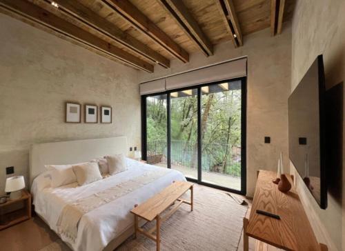 a bedroom with a large bed and a large window at Riverside Haven Elegant House with Serene Forest in San Simon El Alto