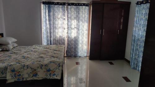 a bedroom with a bed and a window with curtains at Akkarai Beach Luxury Beach Villa in Chennai